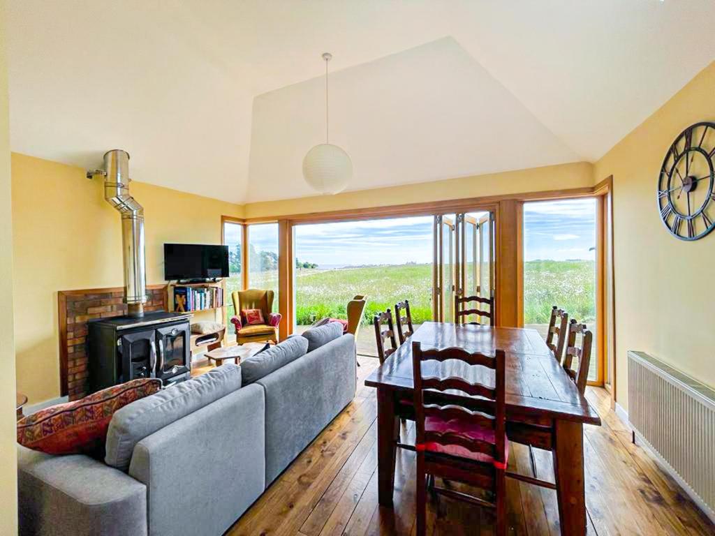 ein Wohnzimmer mit einem Sofa und einem Tisch in der Unterkunft Quirky, Cosy 3BR Cottage With Patio in Canty Bay, Sleeps 10 in North Berwick