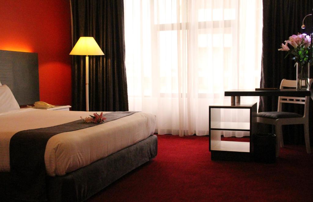 a hotel room with a bed and a desk and window at Grand Riverview Hotel in Kota Bharu