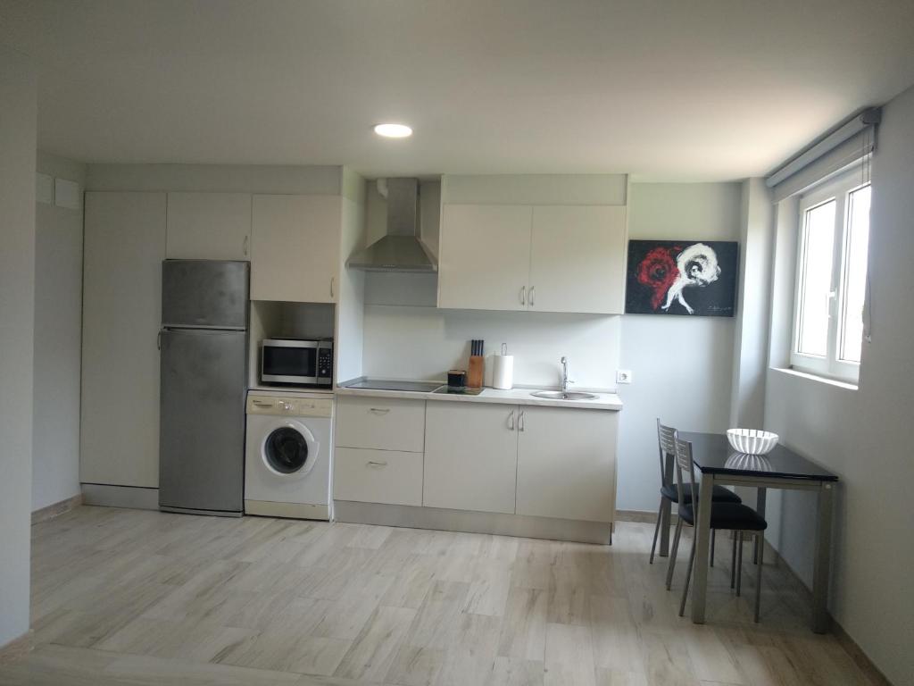 a kitchen with white cabinets and a table and a refrigerator at Casa Eduardo 1 in El Puente