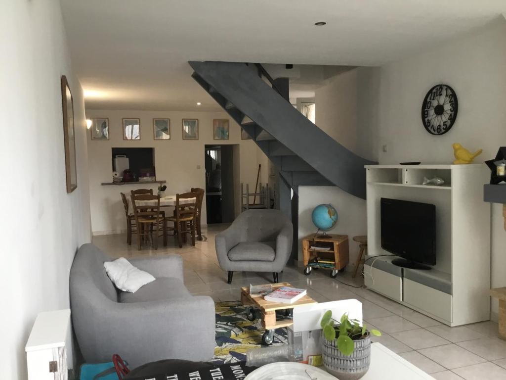 een woonkamer met een bank en een trap bij Maison de centre ville 6 personnes in Précigné