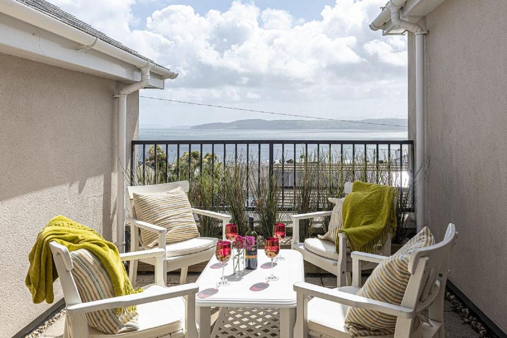 a balcony with chairs and a table with wine glasses at The Penthouse in Benllech