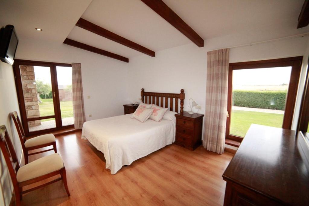 ein Schlafzimmer mit einem Bett und zwei Fenstern in der Unterkunft Casa La Tortola in Vitigudino