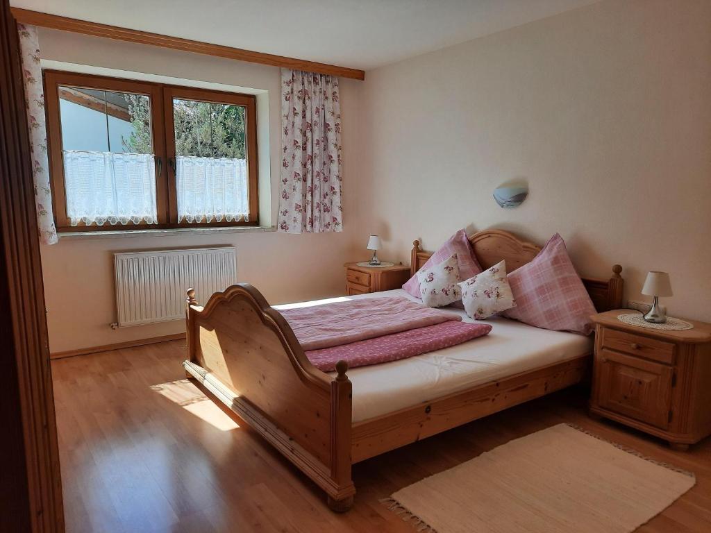 1 dormitorio con cama de madera y ventana en Ferienwohnung Erhart Scheffau, en Scheffau am Wilden Kaiser
