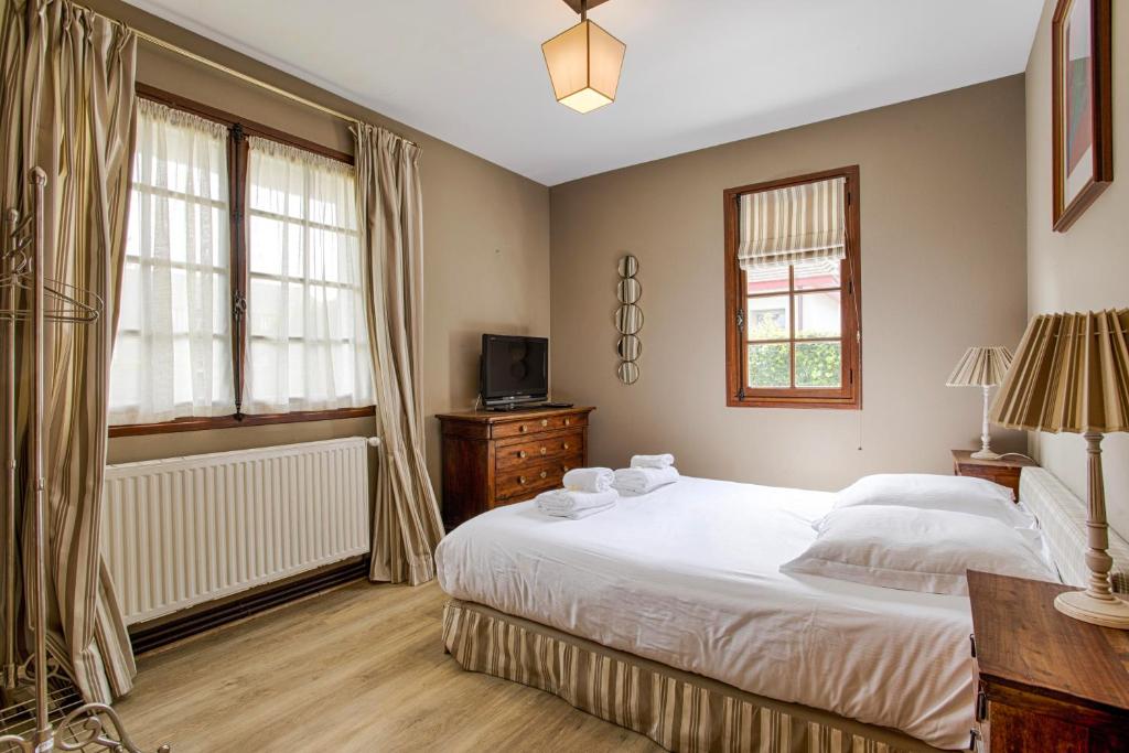 a bedroom with a large white bed and two windows at Luxueuse Chaumière 4 Chambres avec jardin in Deauville
