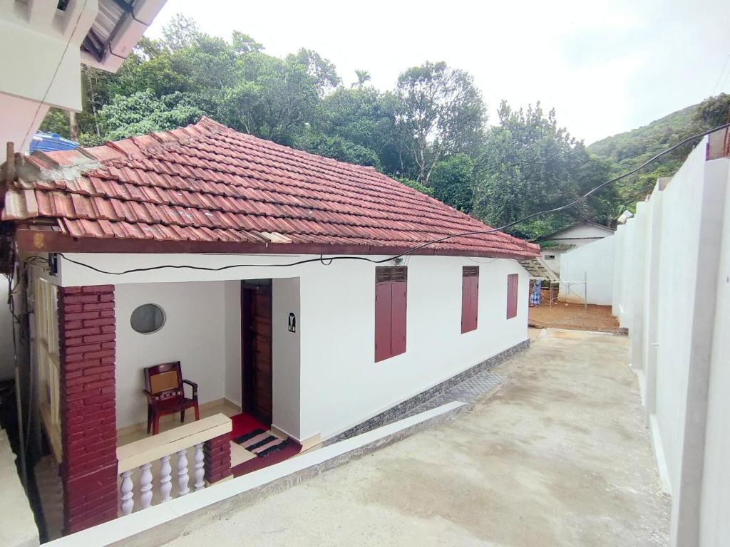 a small white house with a red roof at Olivia Homestay Idukki in Idukki