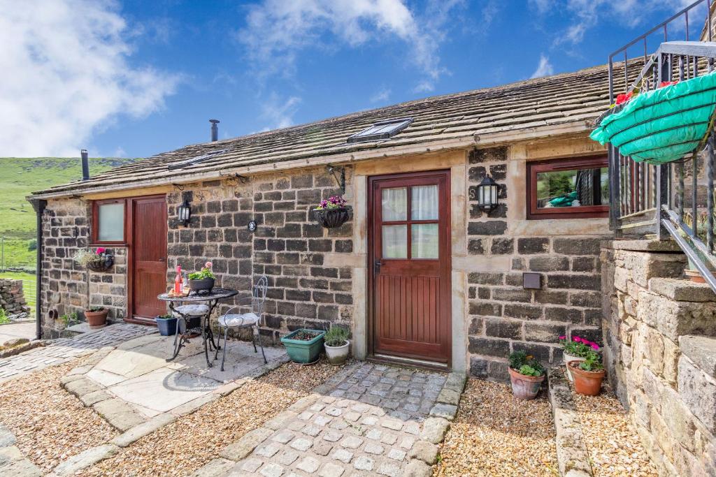 un cottage in pietra con una porta rossa e un tavolo di Jim's Barn a Diggle