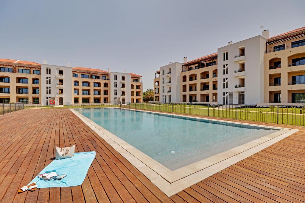 a woman laying on a towel next to a swimming pool at Andiamo Apartment in Vilamoura