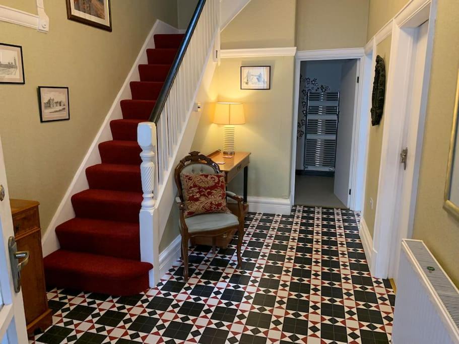 un pasillo con una escalera roja con una silla y una mesa en Heather Glen. Six bedroom home near the sea., en Blackpool