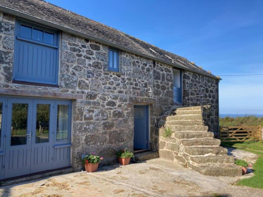 una casa de piedra con una puerta azul y escaleras en Barn conversion in Zennor en St Ives