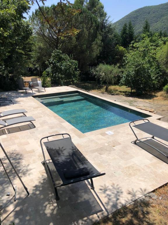 a swimming pool with two chairs and a table and a chair at Les Dames de Saint Florent in Saint-Florent-sur-Auzonnet