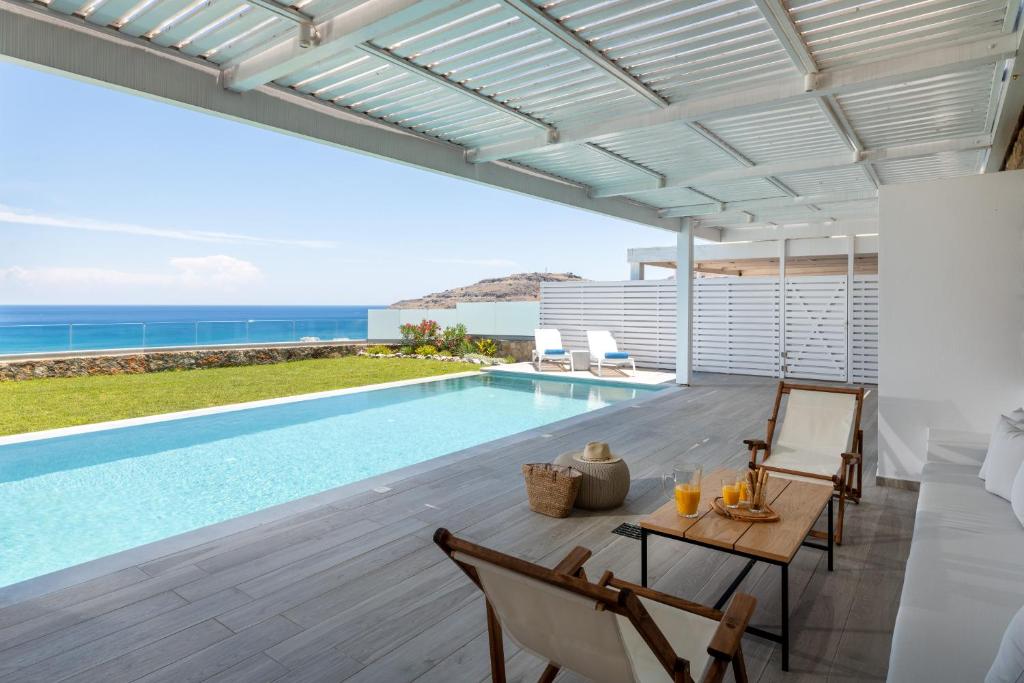 eine Villa mit einem Pool und einer Terrasse mit einem Tisch in der Unterkunft Villa Akrotiri in vlicha