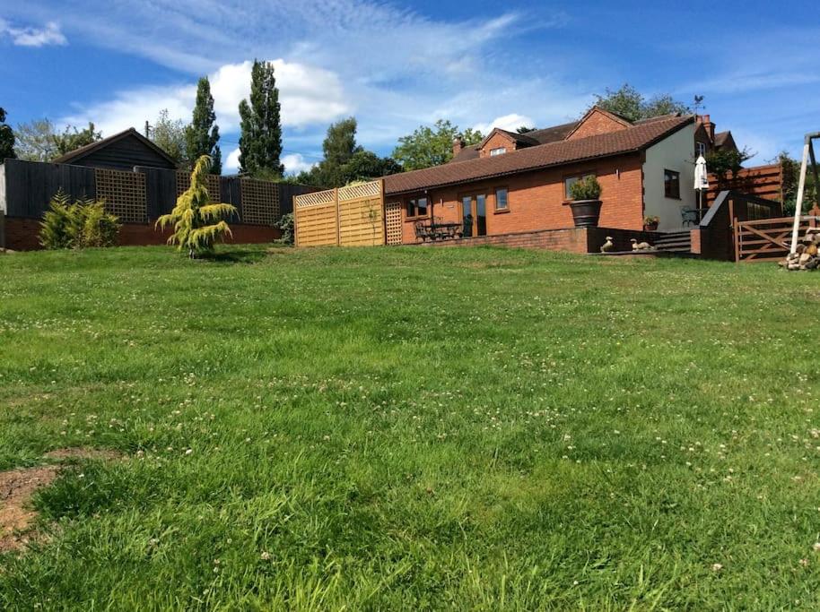 un gran patio con una casa al fondo en Woodcutters Barn, overlooking Ledbury & Malvern Hills, en Ledbury