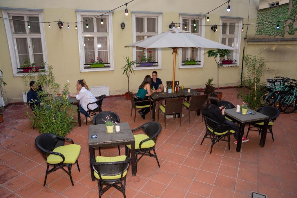 MP Hostel Budapest في بودابست: مجموعة من الناس يجلسون على الطاولات في المطعم