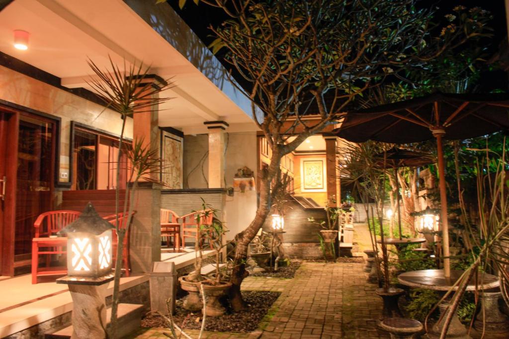 a patio with plants and tables and an umbrella at Kubu Nusa in Nusa Lembongan