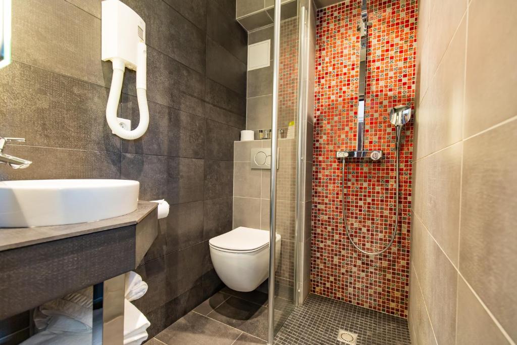 a bathroom with a toilet and a sink and a shower at Hotel Aguado in Dieppe