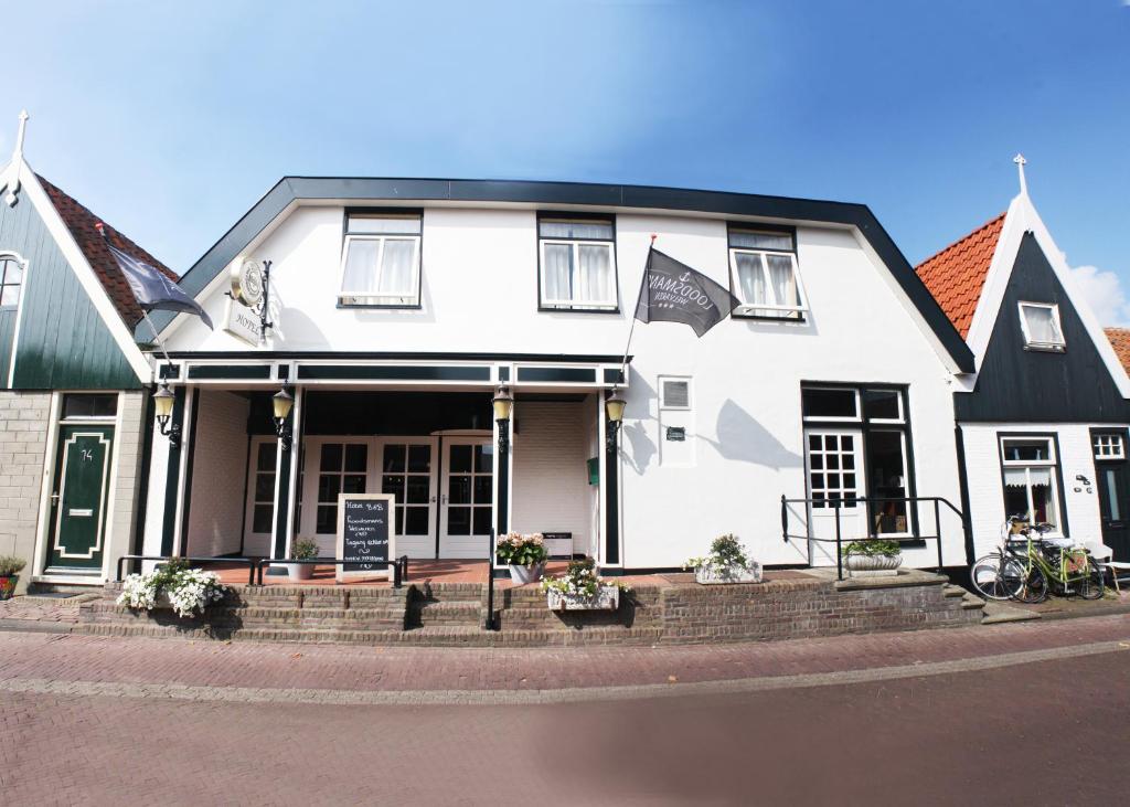 une maison blanche avec un toit noir dans l'établissement Hotel-Restaurant Loodsmans Welvaren, à Den Hoorn