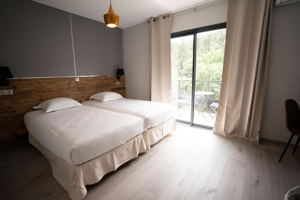 a bedroom with a large bed and a large window at Hôtel Les Vignes in Chassiers