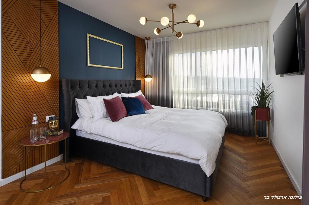 1 dormitorio con 1 cama grande y pared azul en מוריה גולד - MORIA GOLD, en Manot