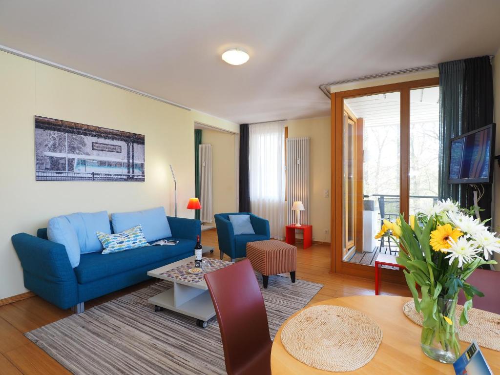 ein Wohnzimmer mit einem blauen Sofa und einem Tisch in der Unterkunft Kaiservillen Heringsdorf - Ferienwohnung mit 1 Schlafzimmer und Balkon D134 in Heringsdorf