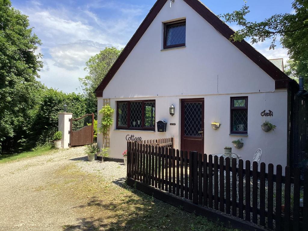 a white house with a fence in front of it at Bosvean Cottage in Bude