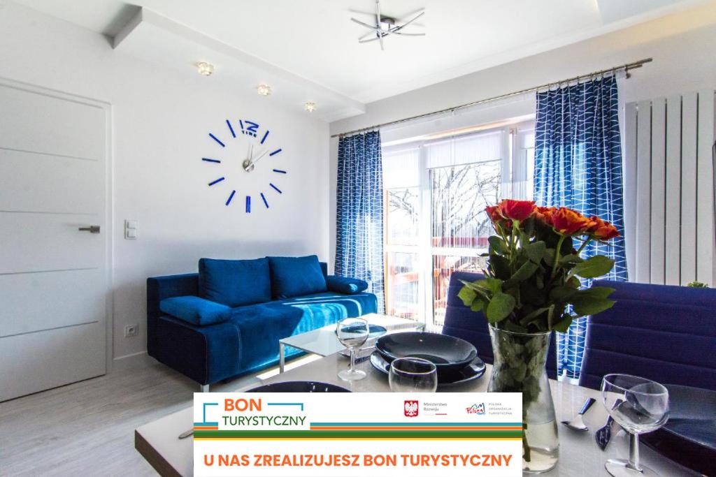 a living room with a blue couch and a clock on the wall at Apartamenty Izerskie - ul. Sienkiewicza 9 in Świeradów-Zdrój