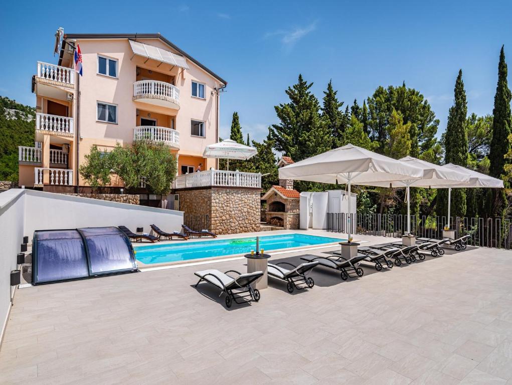 a swimming pool with chairs and umbrellas next to a building at Apartments Prkačin in Starigrad-Paklenica