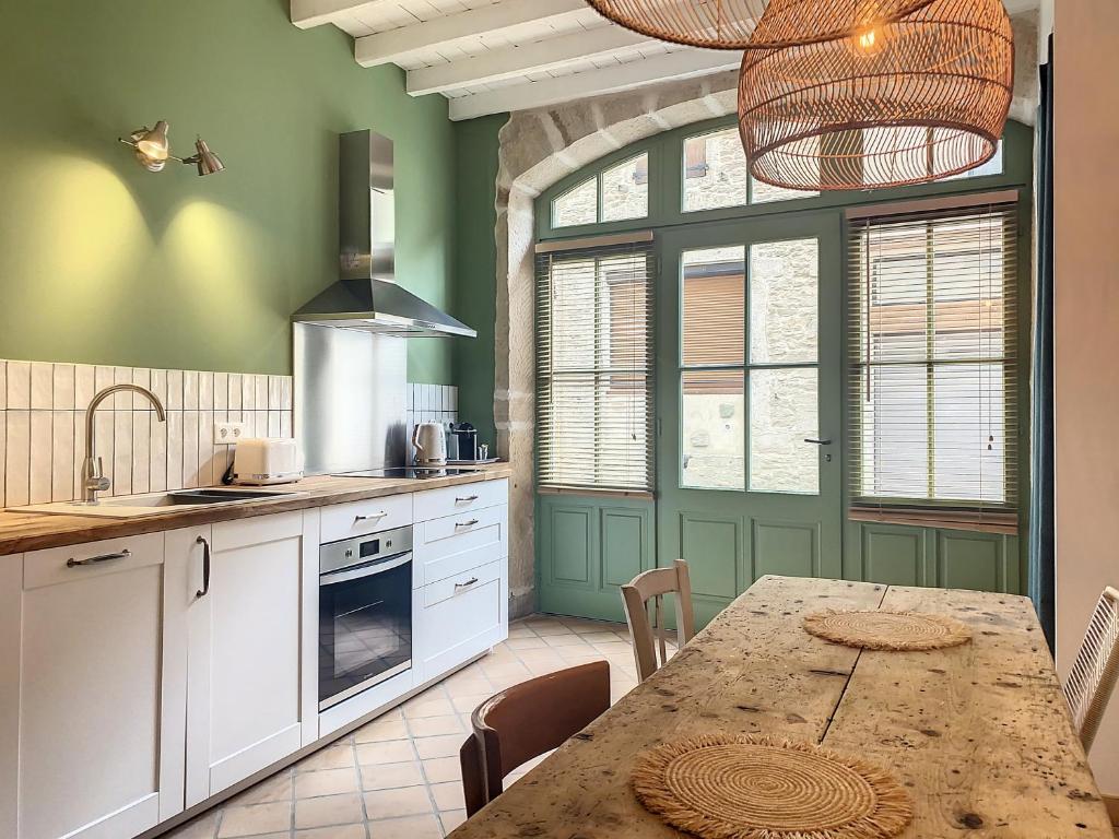 uma cozinha com uma mesa de madeira e uma cozinha com paredes verdes em La Galerie em Saint-Alban-de-Roche
