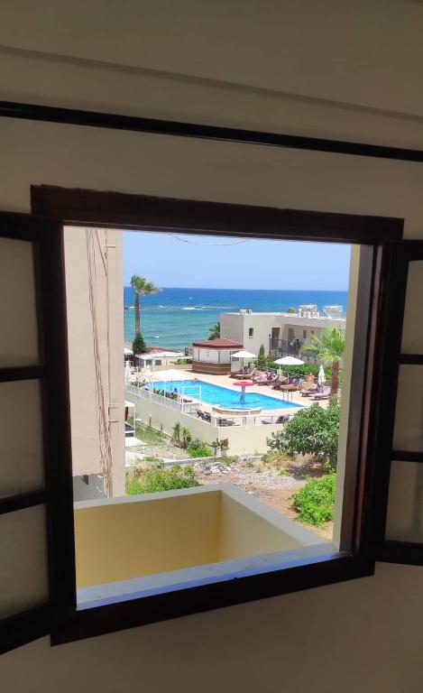 a window with a view of a pool and the ocean at Dedalos n3 Sea View apartment-30 metres from the beach in Stalís