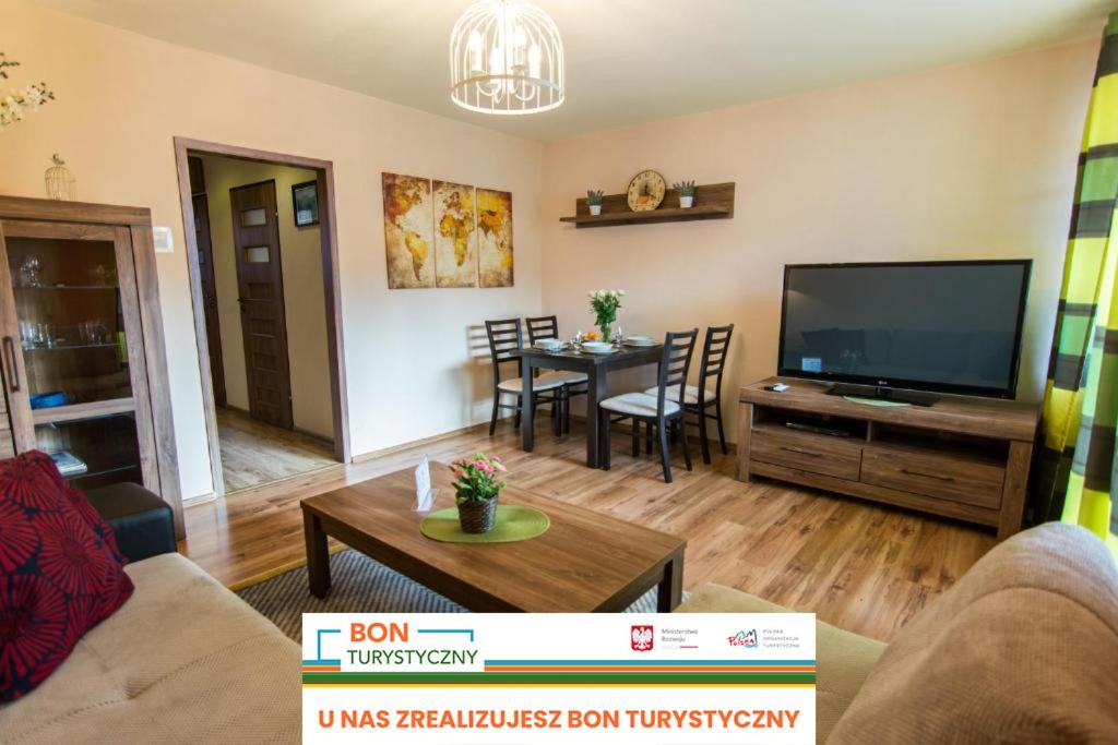 a living room with a television and a table at Apartamenty Izerskie - Wyszyńskiego in Świeradów-Zdrój