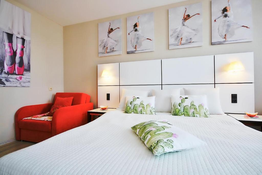 コウォブジェクにあるApartment prywatny 725 Diwa SPA w kompleksie hotelowym w Kolobrzegu ul Kosciuszki 16のベッドルーム(白い大型ベッド1台、赤い椅子付)