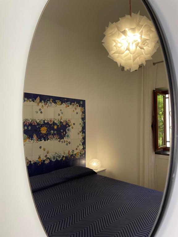 a mirror reflecting a bedroom with a bed and a painting at La Corte dei Naviganti B&B - Amalfi Coast - Cetara in Cetara