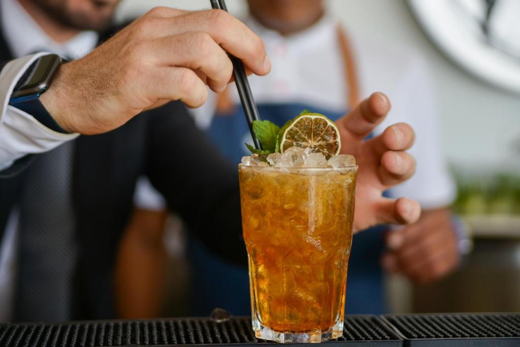 a man is stirring a drink with a straw at Lloret Vibe Affiliated by FERGUS in Lloret de Mar