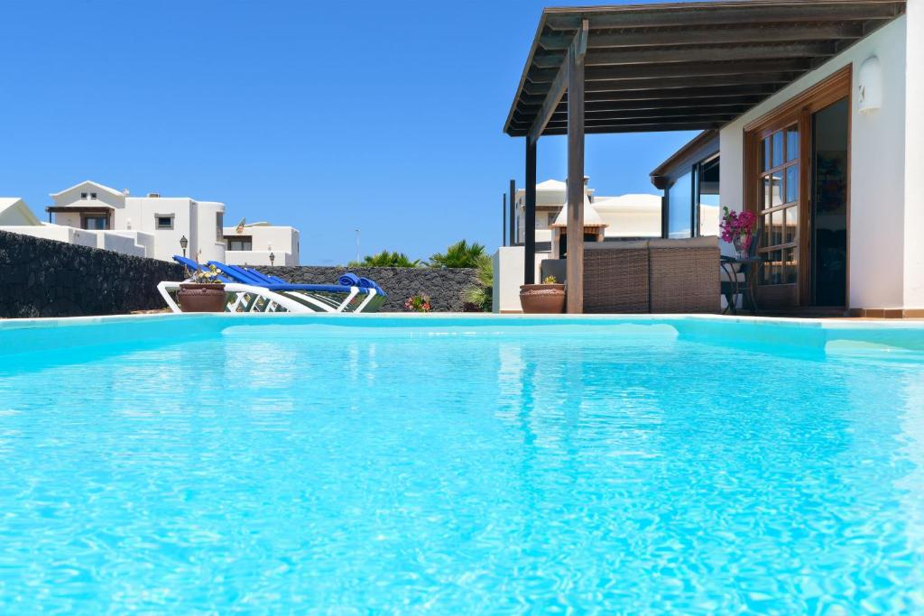 une grande piscine bleue en face d'une maison dans l'établissement Hipoclub Villas, Aguamarina 29, à Playa Blanca