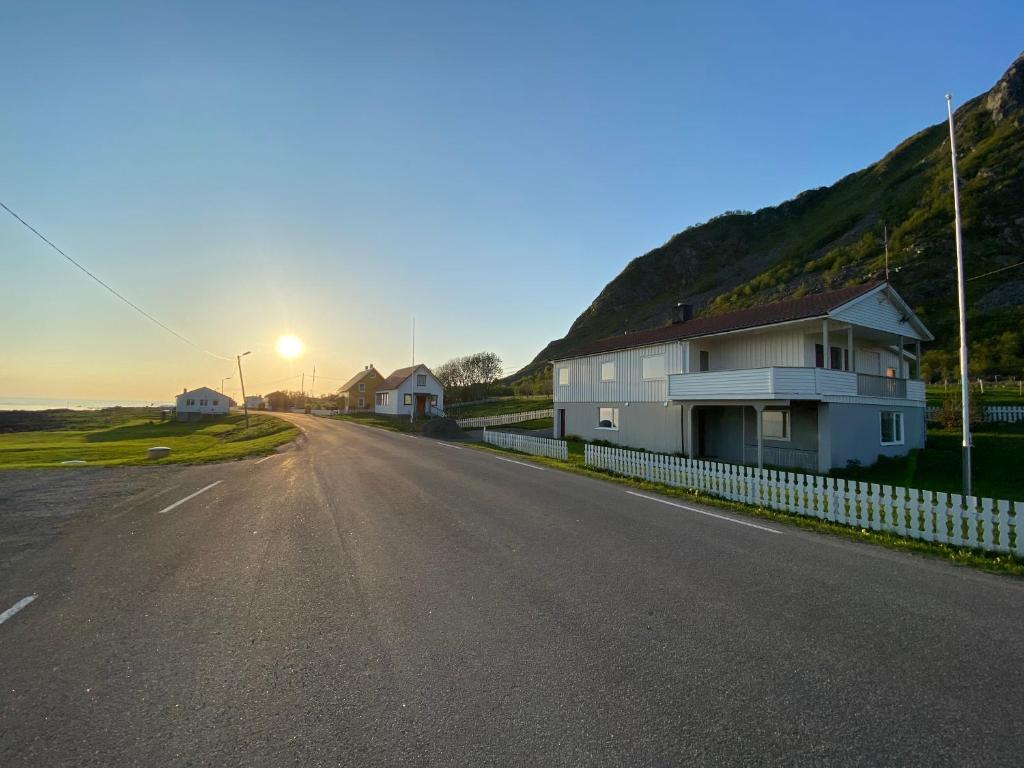 a house on the side of a road with the sunset at Nøssveien 271, 8488 Nøss Andøy in Nøss