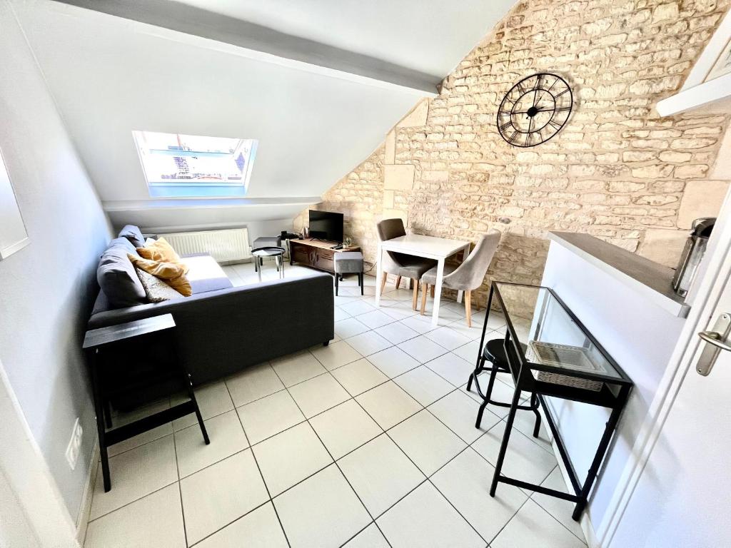 un salon avec un canapé et un mur en pierre dans l'établissement F2 au CALME HYPER CENTRE, à Caen