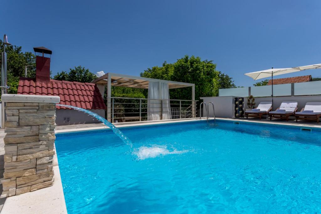 uma piscina com uma fonte de água em Holiday house Mala em Sinj