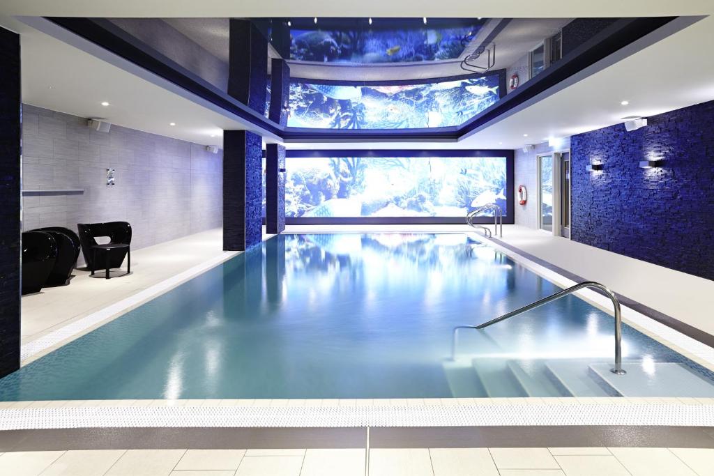 a swimming pool in a house with a ceiling at Novotel London Brentford in Brentford