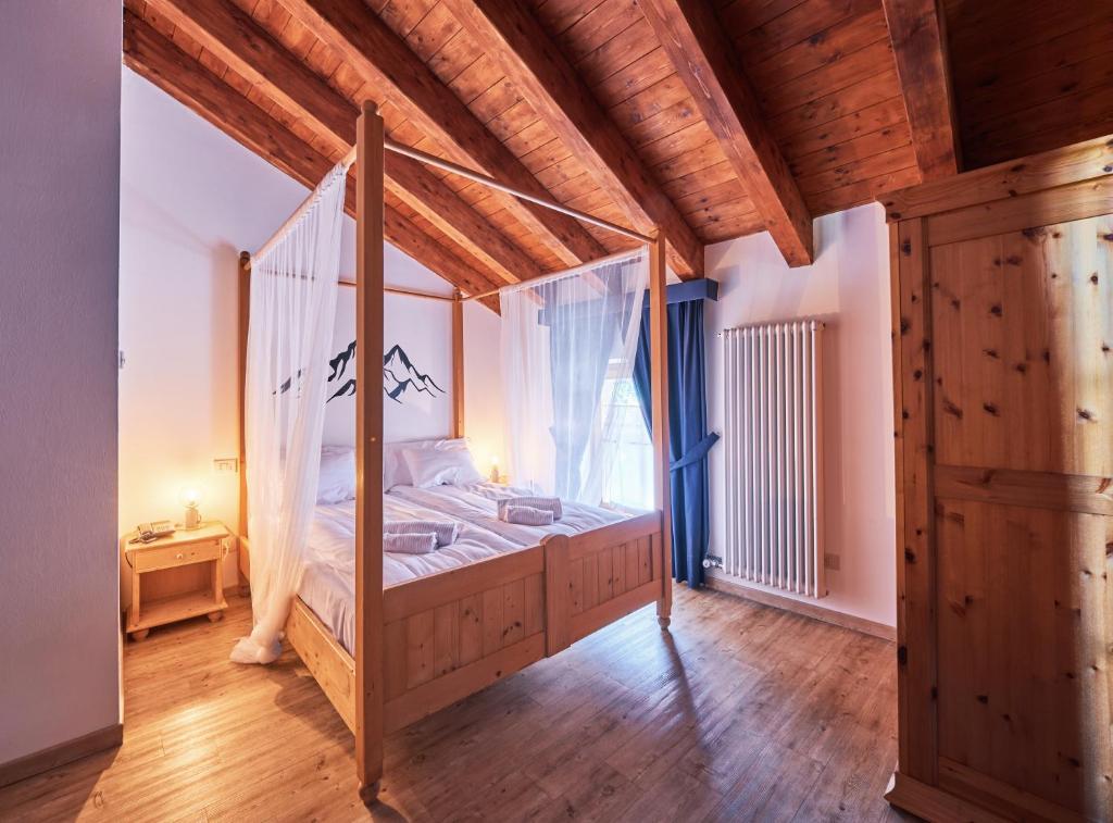 a bedroom with a canopy bed with a window at Hotel Bed & Bike Ledro in Molina di Ledro
