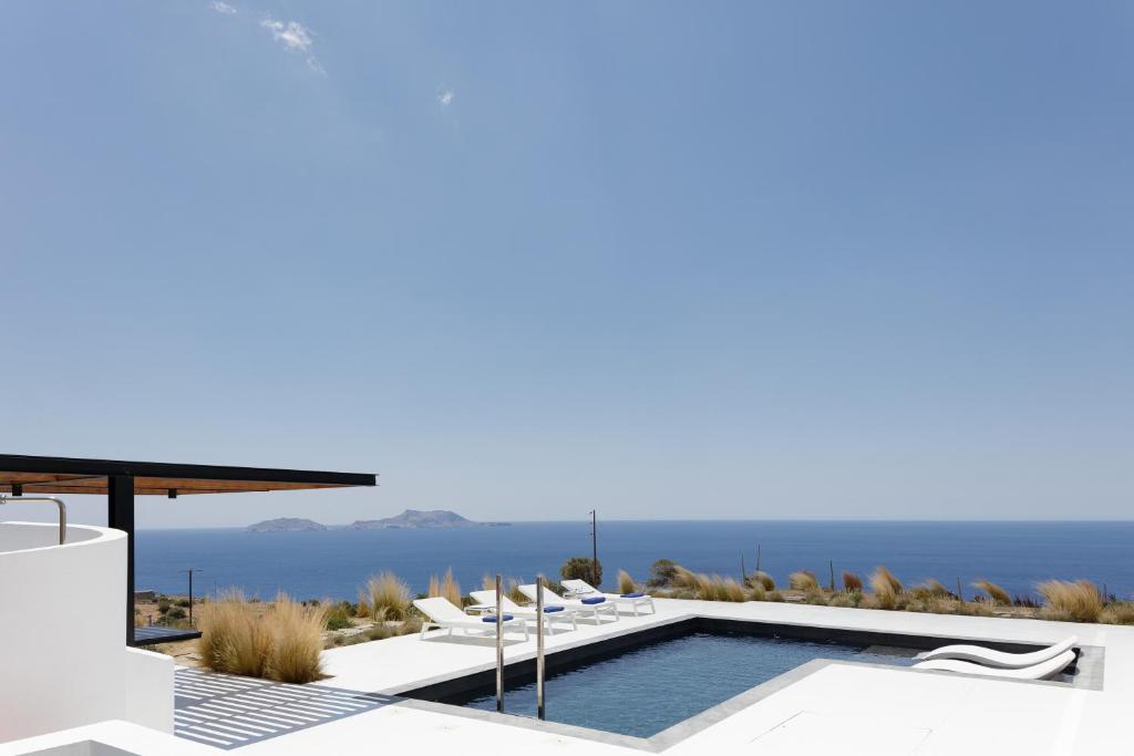 a pool with chairs and the ocean in the background at White Hera in Agios Pavlos