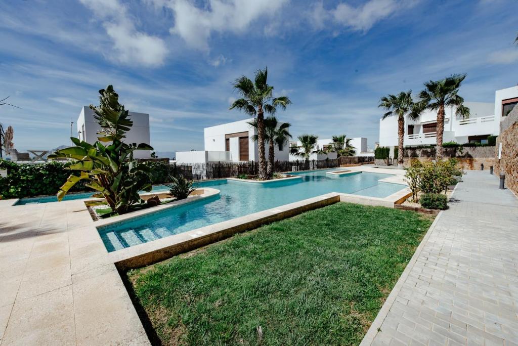 una piscina con césped y palmeras en Casita Rosa en Alicante