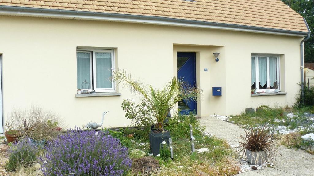 una casa blanca con una puerta azul y algunas flores en Chambres des 24h00 du Mans, en Challes