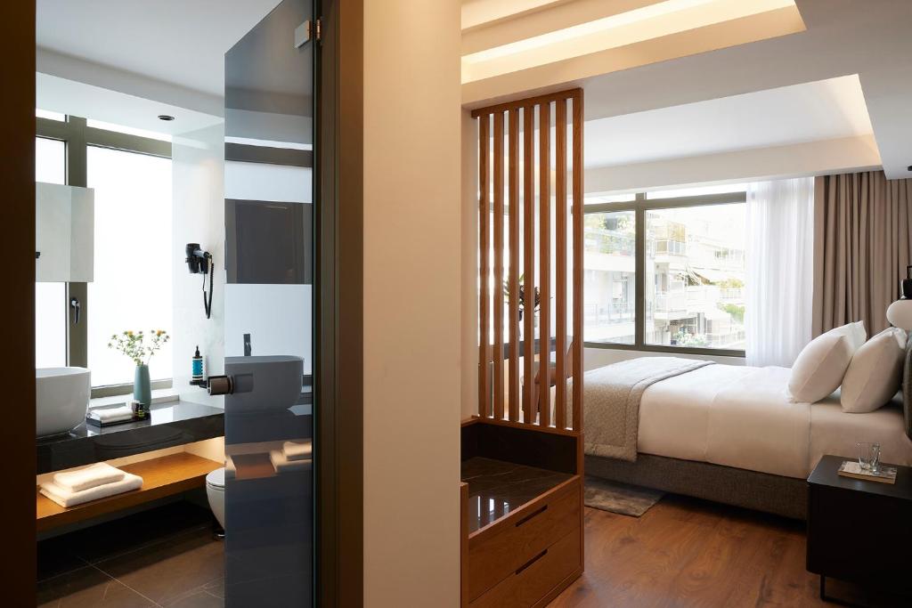 a bedroom with a bed and a bathroom with a window at Teight Hotel in Thessaloniki