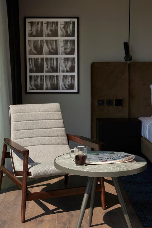 a living room with a chair and a table with a drink on it at Teight Hotel in Thessaloniki