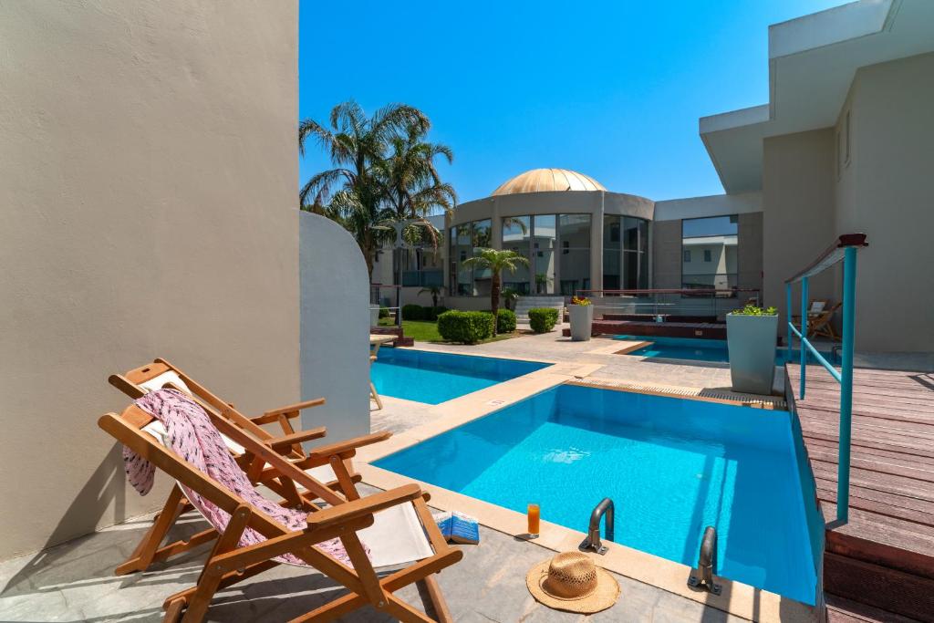 un patio con una silla y una piscina en All Senses Ocean Blue Sea Side Resort - All Inclusive, en Kremasti