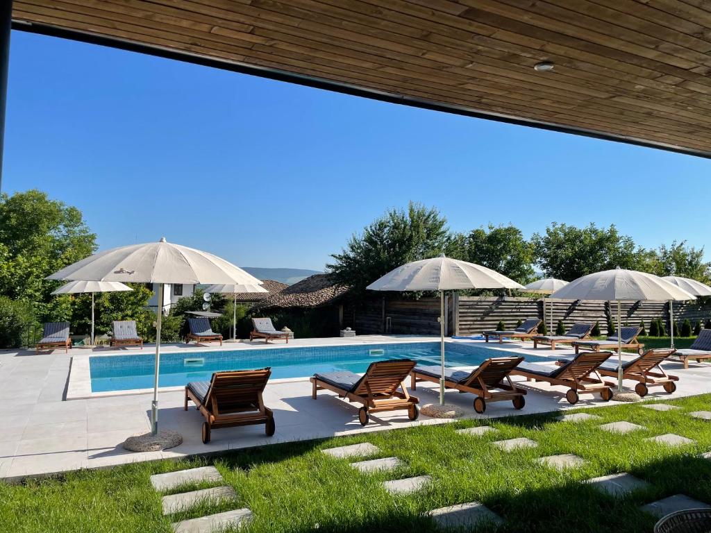 a pool with a bunch of chairs and umbrellas at Mutafova Guest House in Veliki Preslav