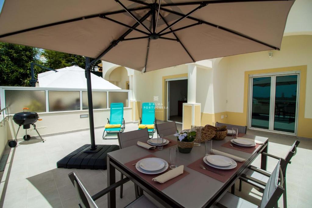 a table with chairs and an umbrella on a patio at Casa Ferreira Encosta dos Salgados - By Dalma Portuguesa in Albufeira