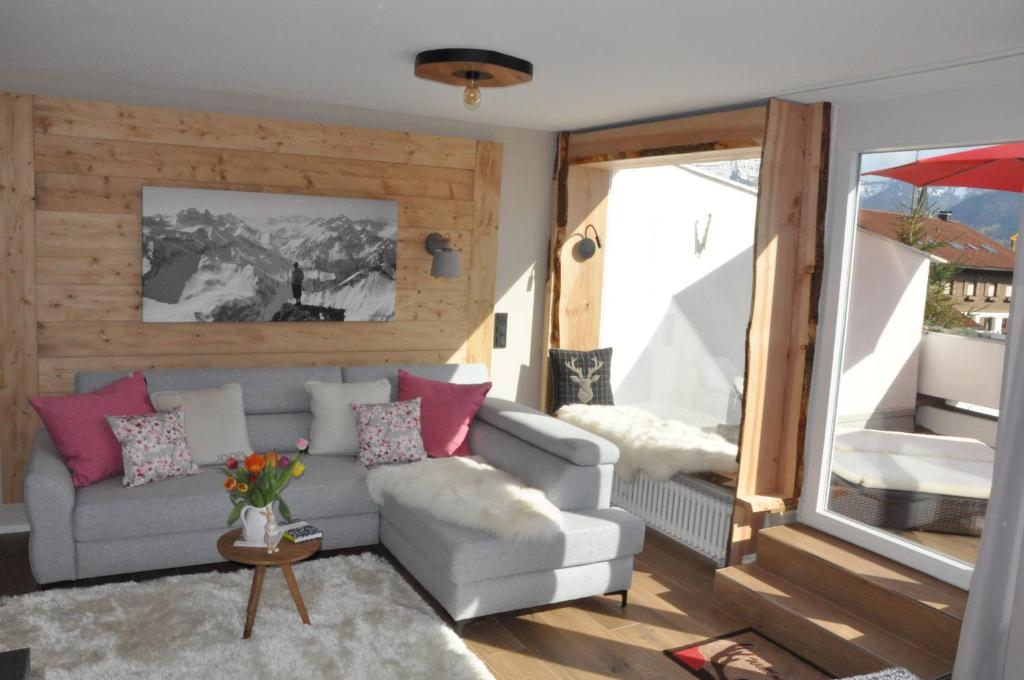 a living room with a gray couch and pink pillows at ALMI - Alpenglück Traumhafte Whg.m.20qm Dachterr. in Oberstaufen