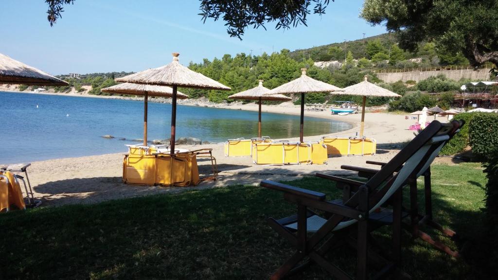 a beach with yellow chairs and umbrellas and the water at Porto Psakoudia in Psakoudia