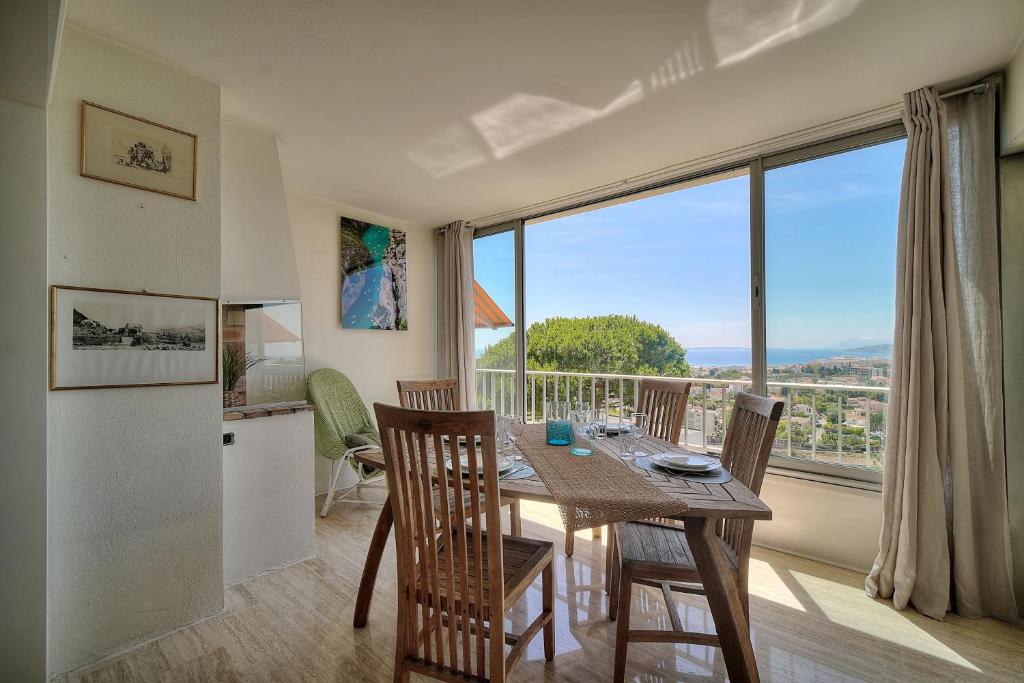 une cuisine et une salle à manger avec une table et une grande fenêtre dans l'établissement Attique Antibois - Piscine - Vue Mer - Parking - Wifi, à Antibes