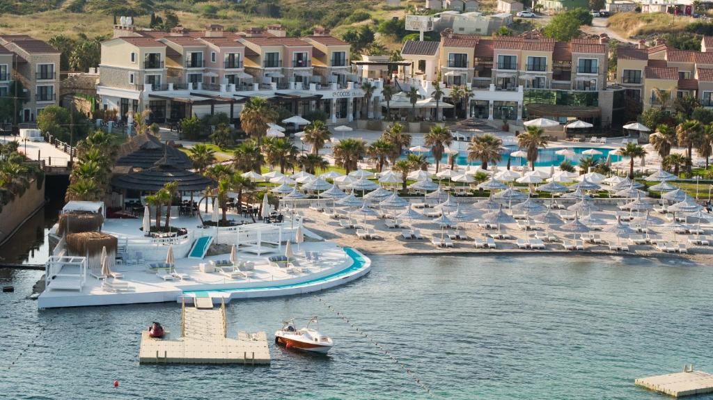 an aerial view of a resort with a boat in the water at Cocos The Club Solto in Alaçatı